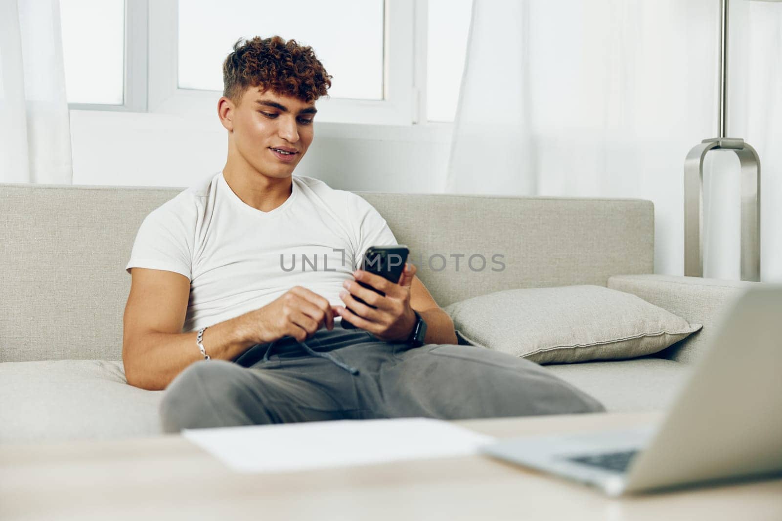 man interior curly using cell online lifestyle young phone home selfies text business mockup technology sofa message freelancer