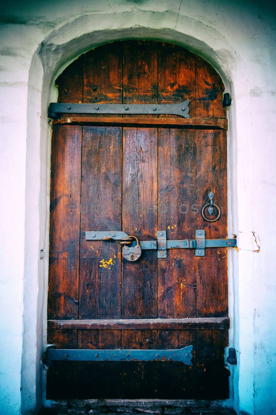 Vintage wooden door with an old rusty padlock. Ancient door in a stone doorway. Vintage camera filter added to image