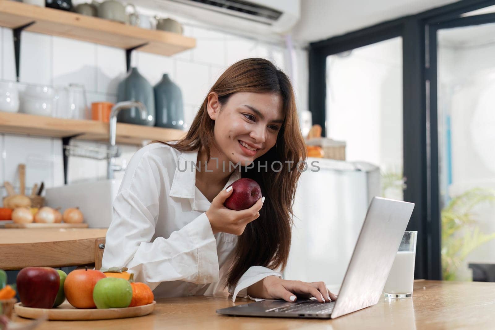 Asian young woman use laptop in the kitchen at home.