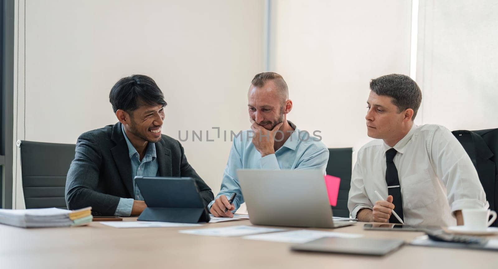 Business team discussing online project, showing computer presentation to skilled team leader. Friendly diverse colleagues working in pairs on laptop.