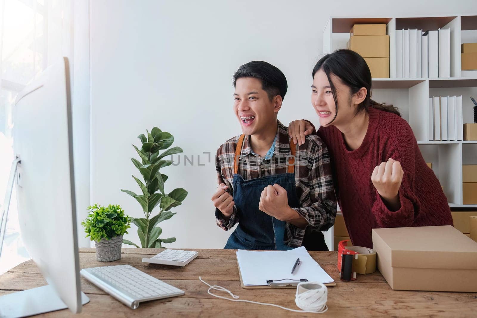 Couple asian young exciting raised hands with orders from customers in laptop. Seller product online concept.