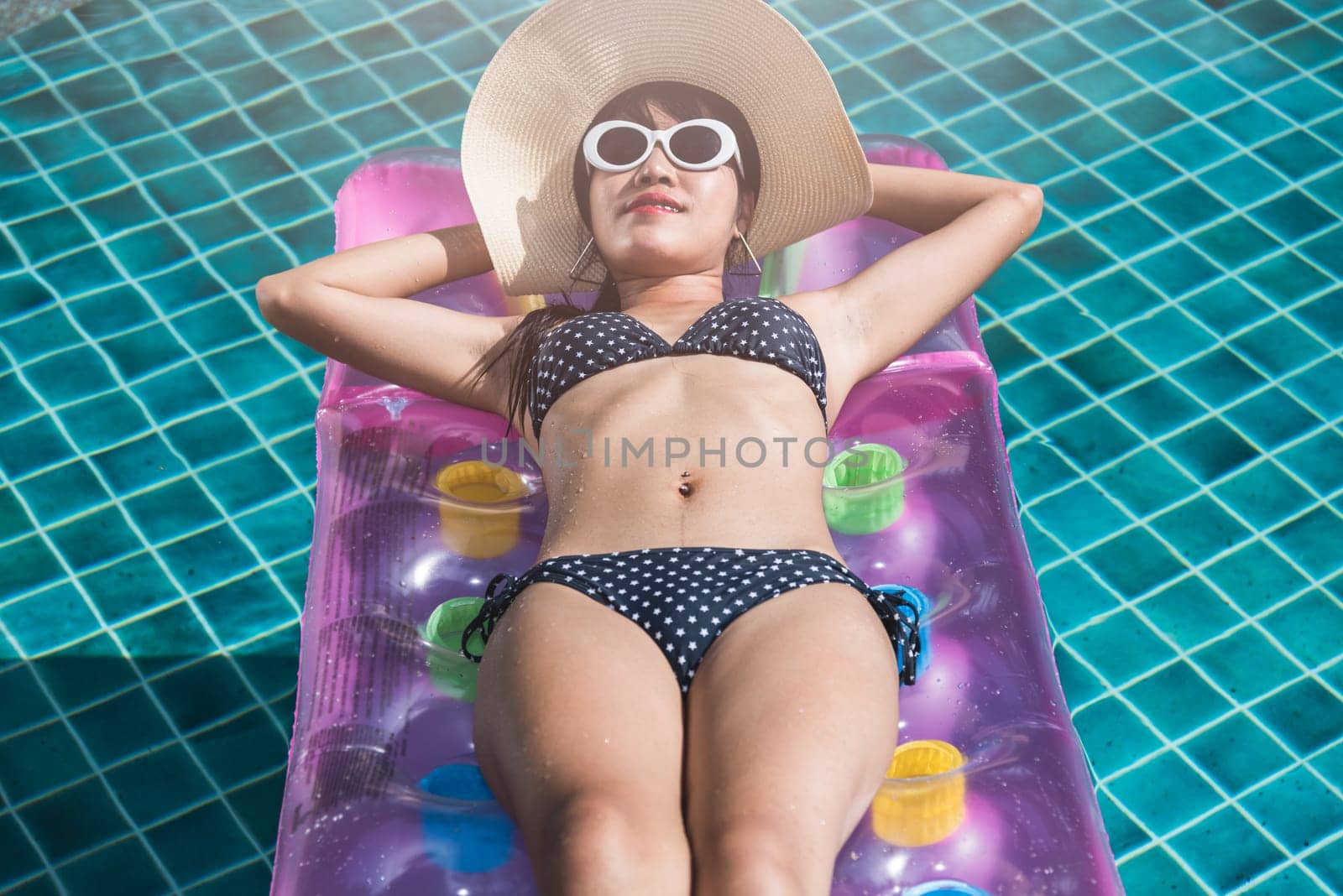 Attractive young sexual young woman in bikini sunbathing on mattress inflatable at swimming pool blue water, female relaxation lying air mattress swims, vacation enjoying on summer season holiday