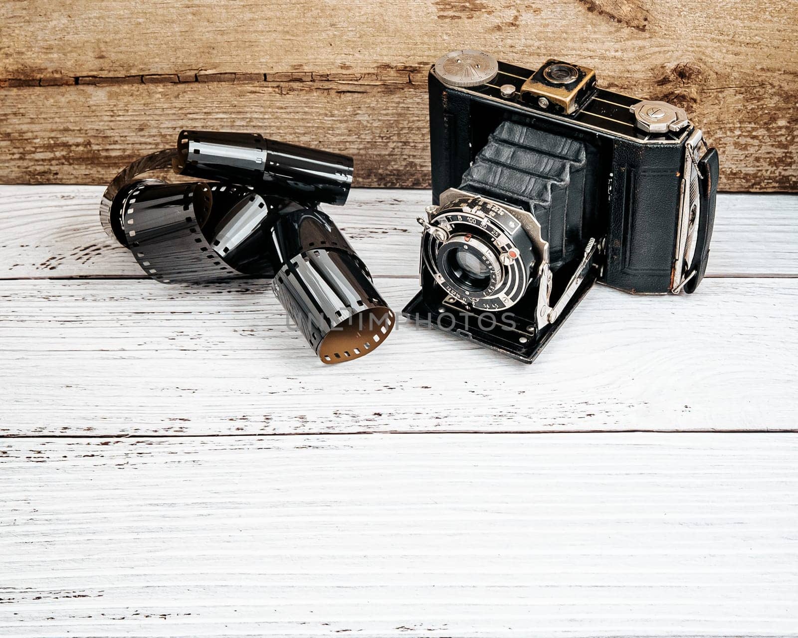 Vintage photo camera with film roll on wooden background.