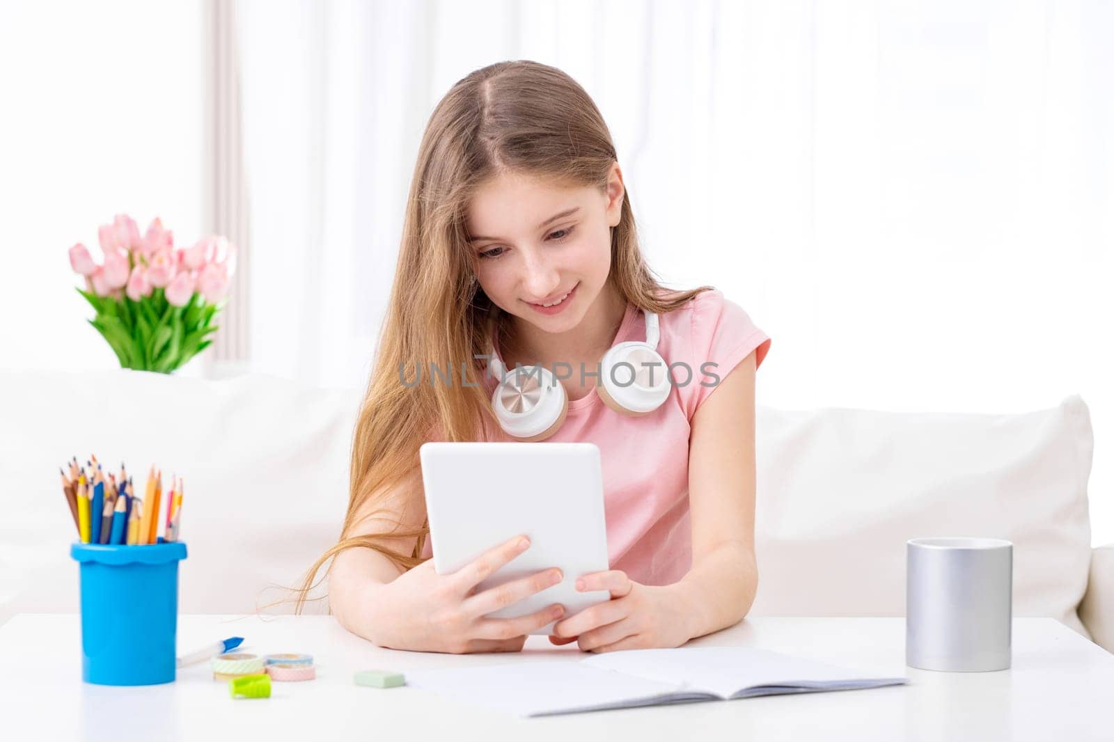 Girl is exploring social networks on her tablet at her working place indoors