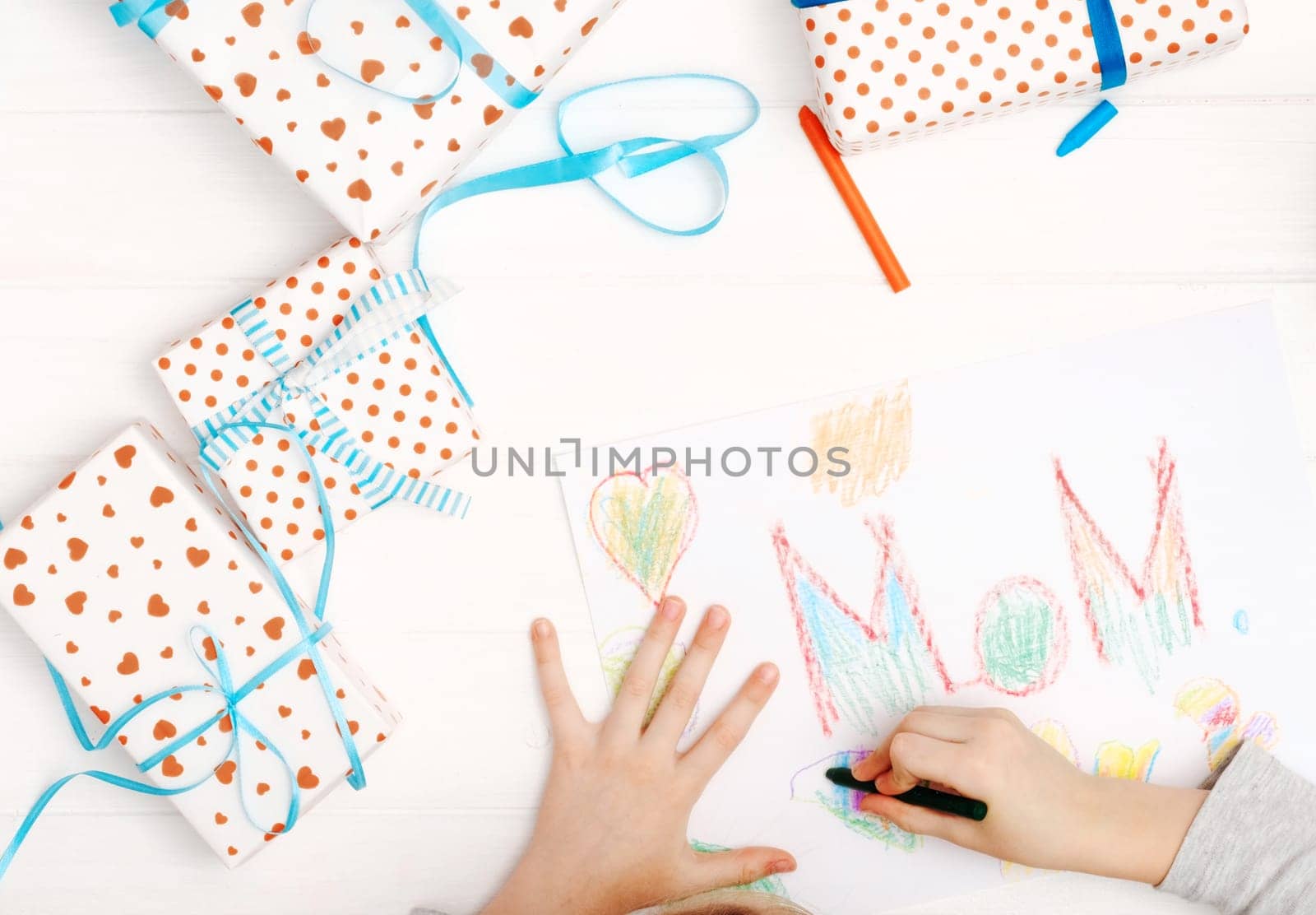 Little girl drawing happy mother's day greeting card with presents on the table