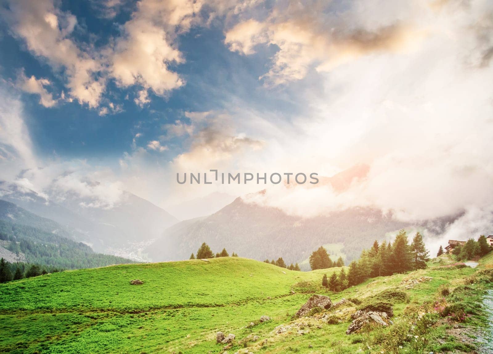 Panorama of cloudy tranquil Alps at sunset