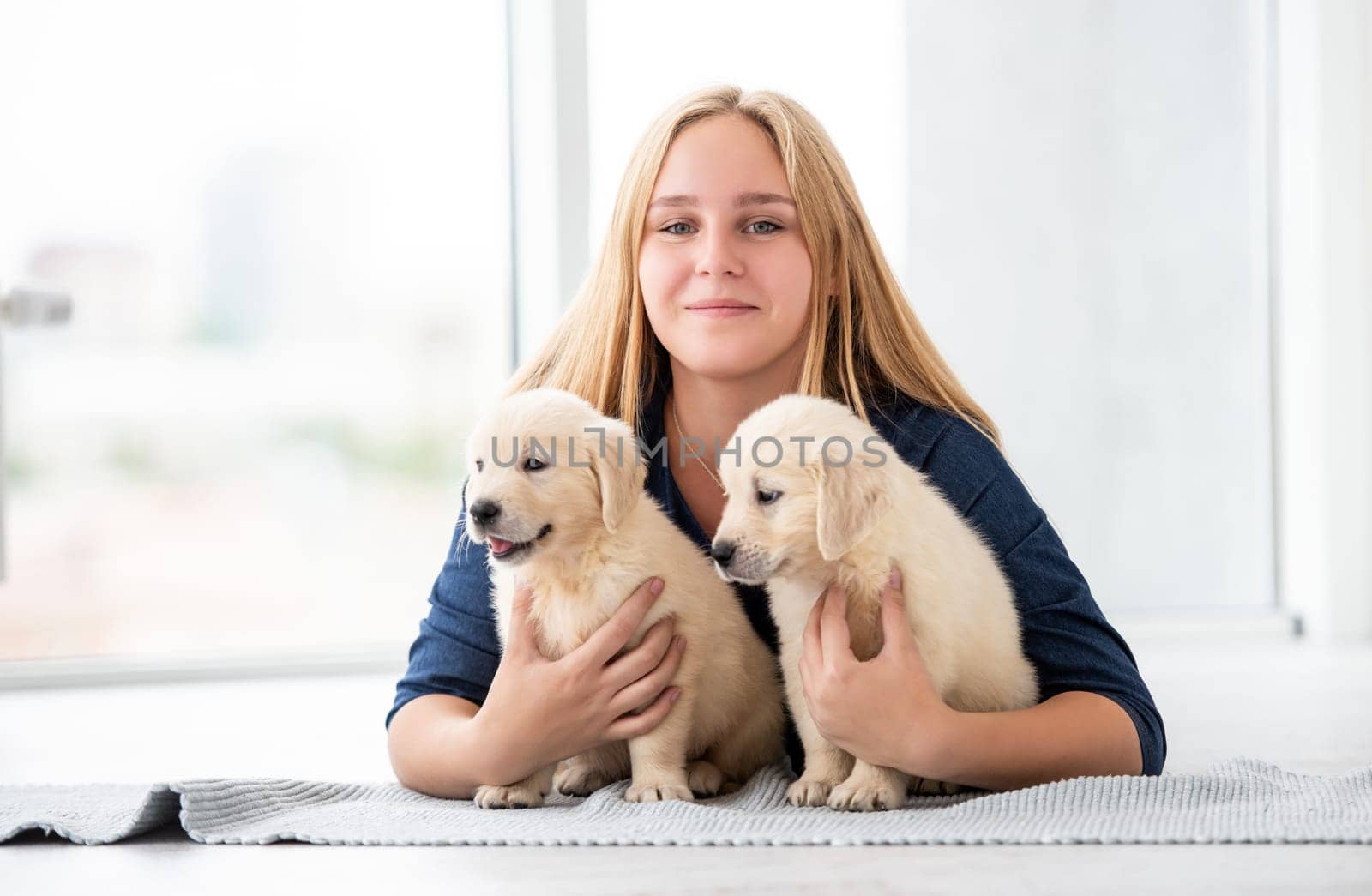 Cute girl hugging lovely puppies on floor indoors