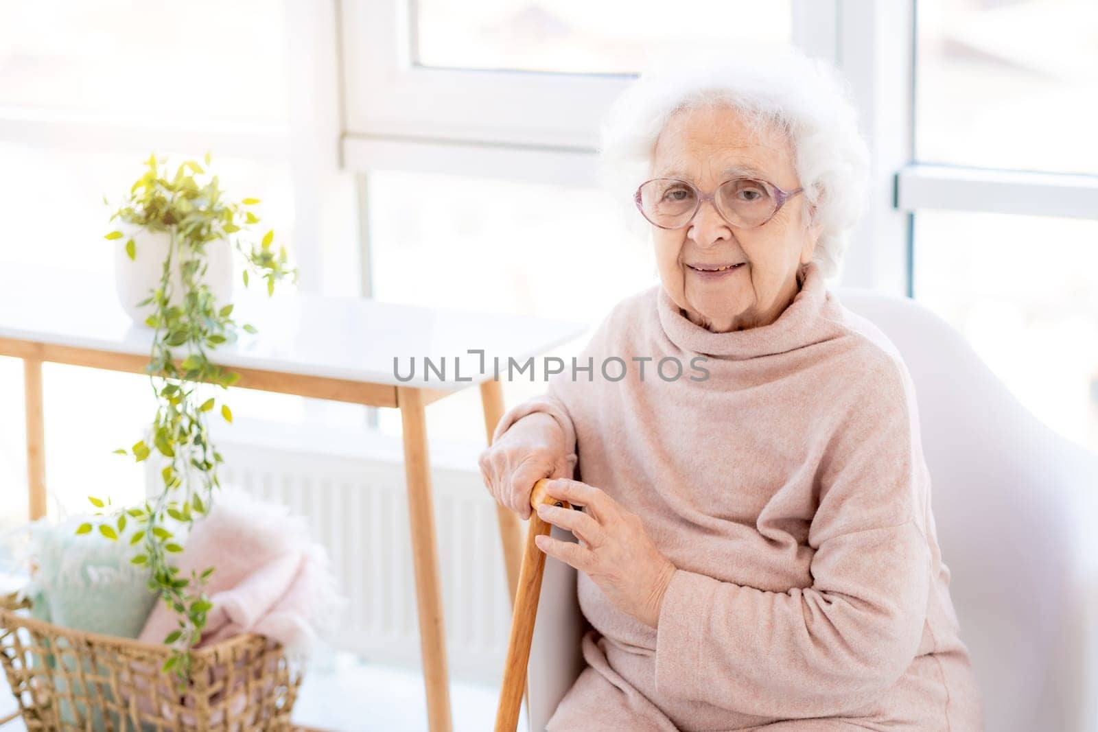 Happy old woman sitting in light interior