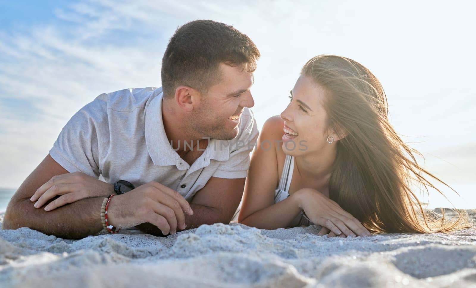 Love, ocean and couple laying on beach, man and woman relax on summer morning date. Travel, sea and happy couple on sand, spending time together in nature and romance on luxury vacation in Australia