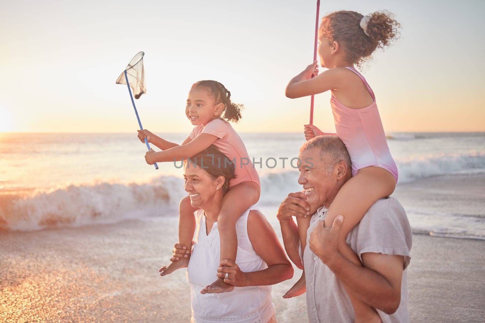 Children, grandparents and piggy back on beach on summer holiday walking in sea sand. Happy family at the ocean on vacation in Mexico. Grandma, grandpa and kids in on a walk in waves at sunset