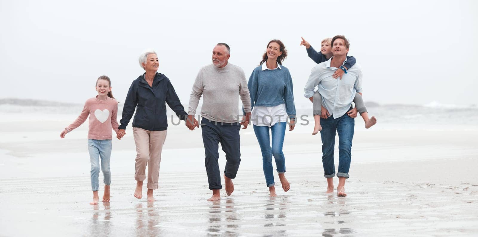 Family, beach and children with grandparents, parents and kids walking in the water on the sand in a summer holiday. Travel, love and vacation with a girl, boy and relatives taking a walk by the sea by YuriArcurs