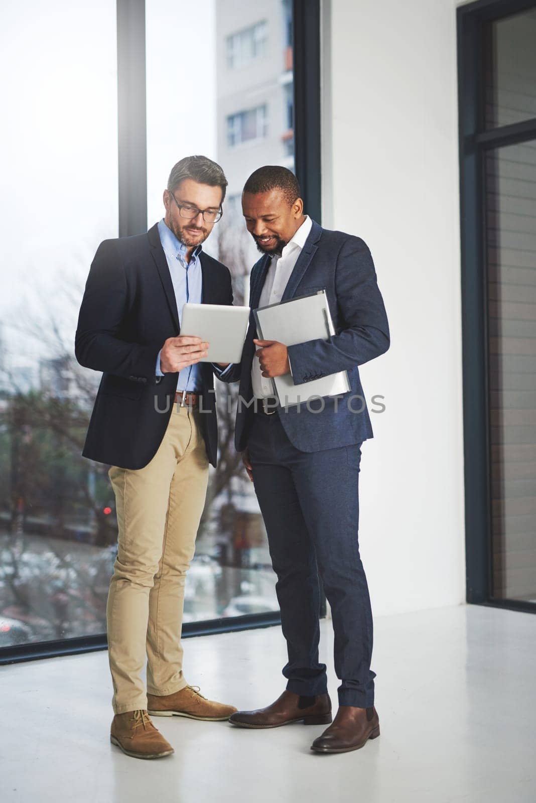 Shot of two businessmen using a digital tablet together at work.