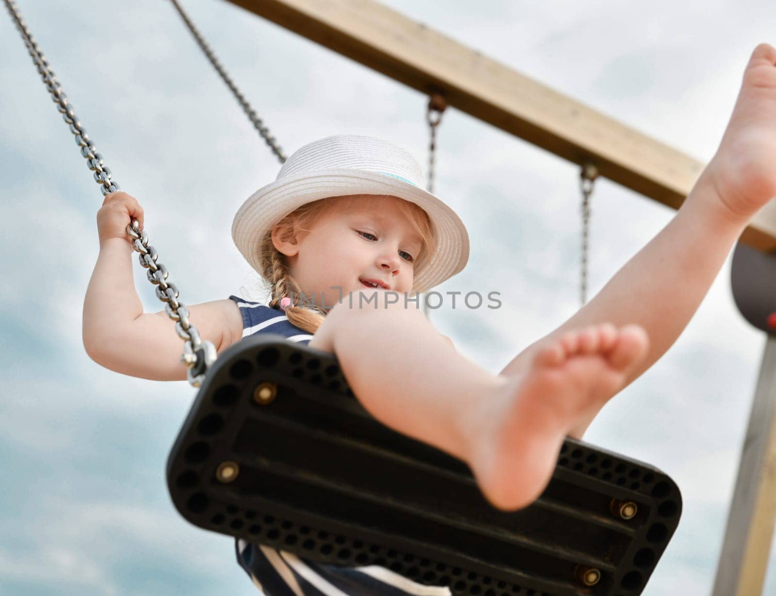 Girl 3 years old riding on a swing without shoes