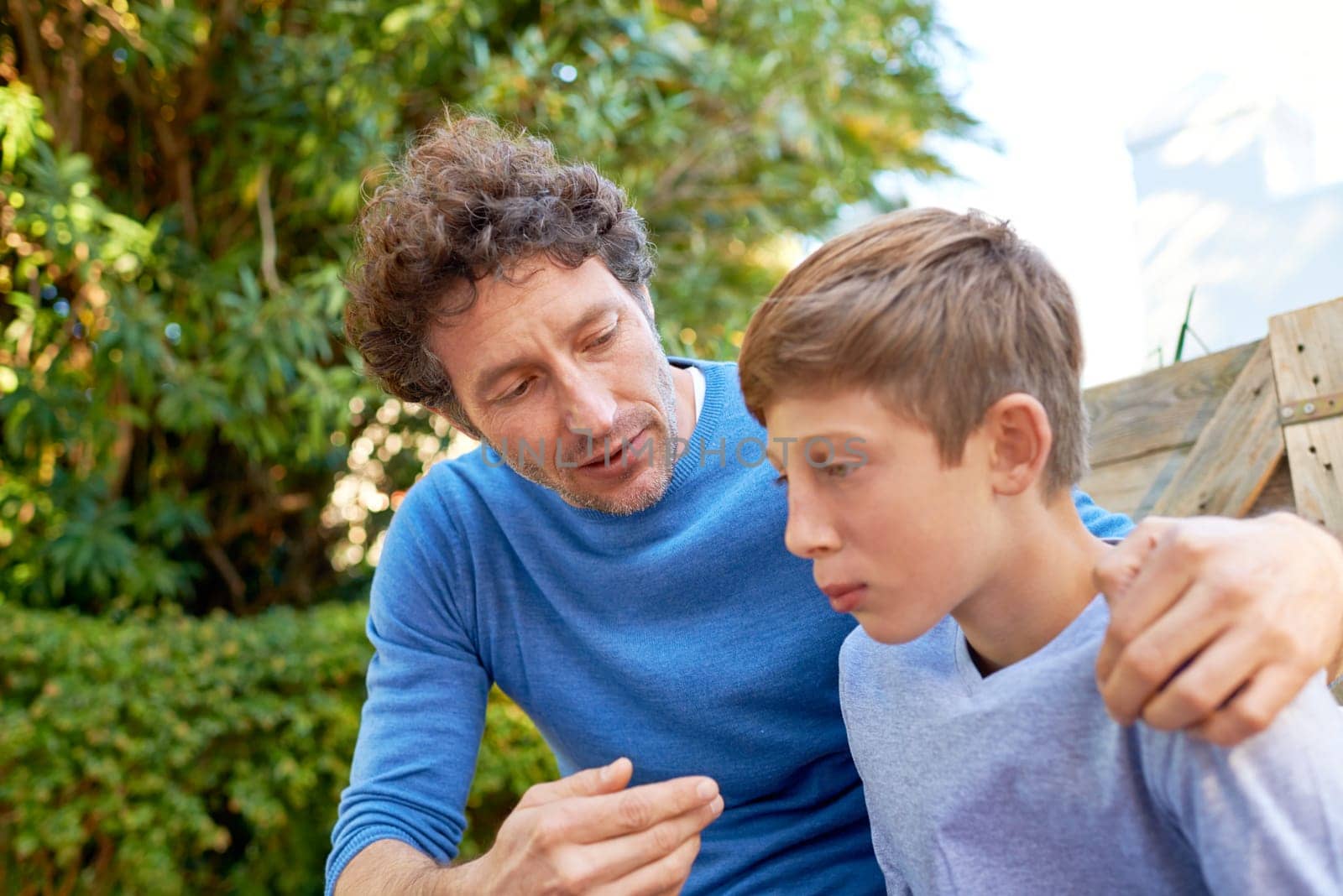 Family, father talking with son in backyard, bonding with love and care, communication and relationship. Man with sad teen boy, help with advice at home and outdoor together with trust and support.
