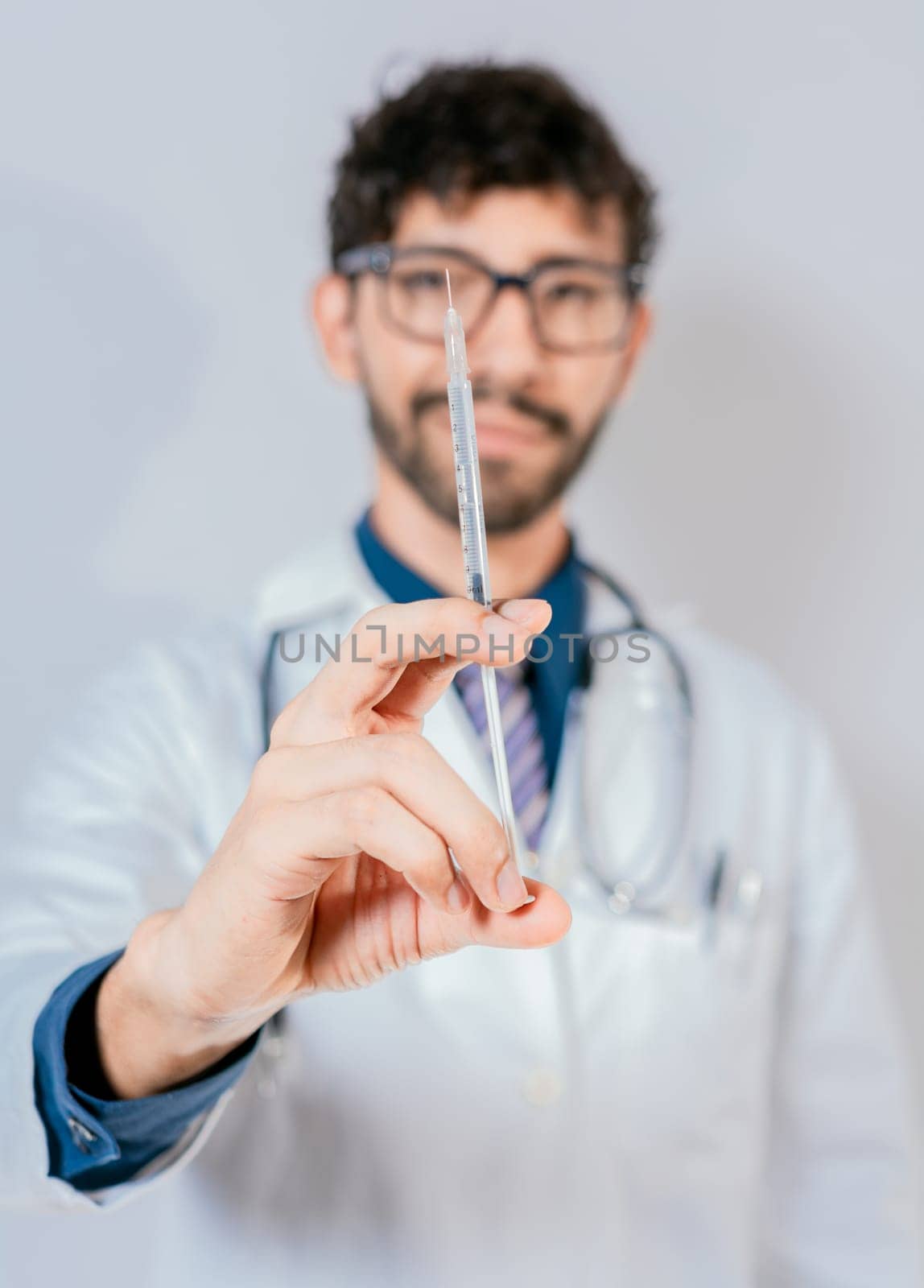 Close up of doctor holding a syringe isolated. Smiling doctor holding a syringe on isolated background