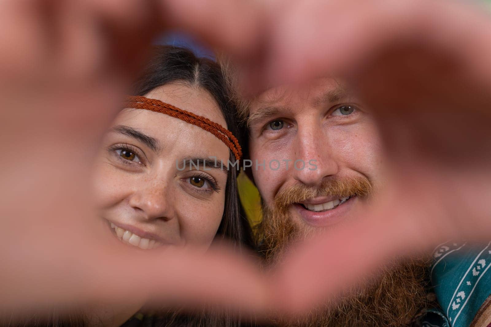 Young family married hippie couple man woman makes symbol of love, showing heart sign to camera, express romantic feelings, express sincere positive feelings at home. Husband, wife together in room