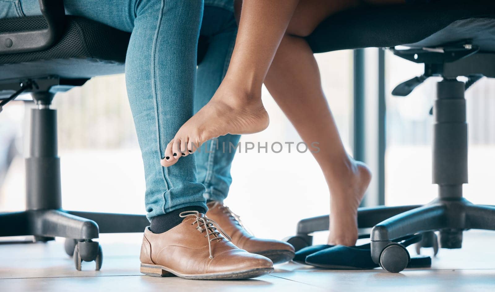 Feet, flirt and affair with a work romance between and business man and woman in the office together. Couple, shoes and love with a male and female flirting under a table at work in infidelity.