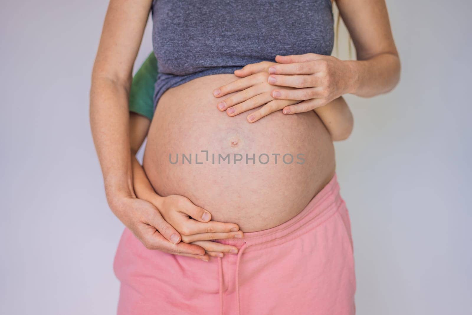 Young beautiful pregnant woman and eldest son. The cute boy put his hands on his mother's belly. Expecting a baby in the family concept. Preparing an older child for a younger one.