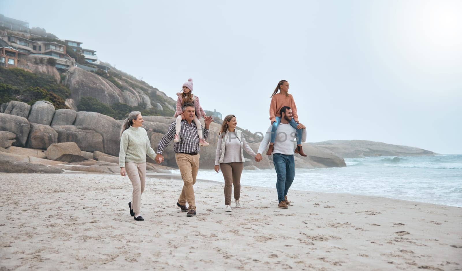Family, walking and holding hands on beach holiday vacation. Happy grandparents, parents and children smile together for love trust bonding holiday or quality time adventure on sand ocean water.