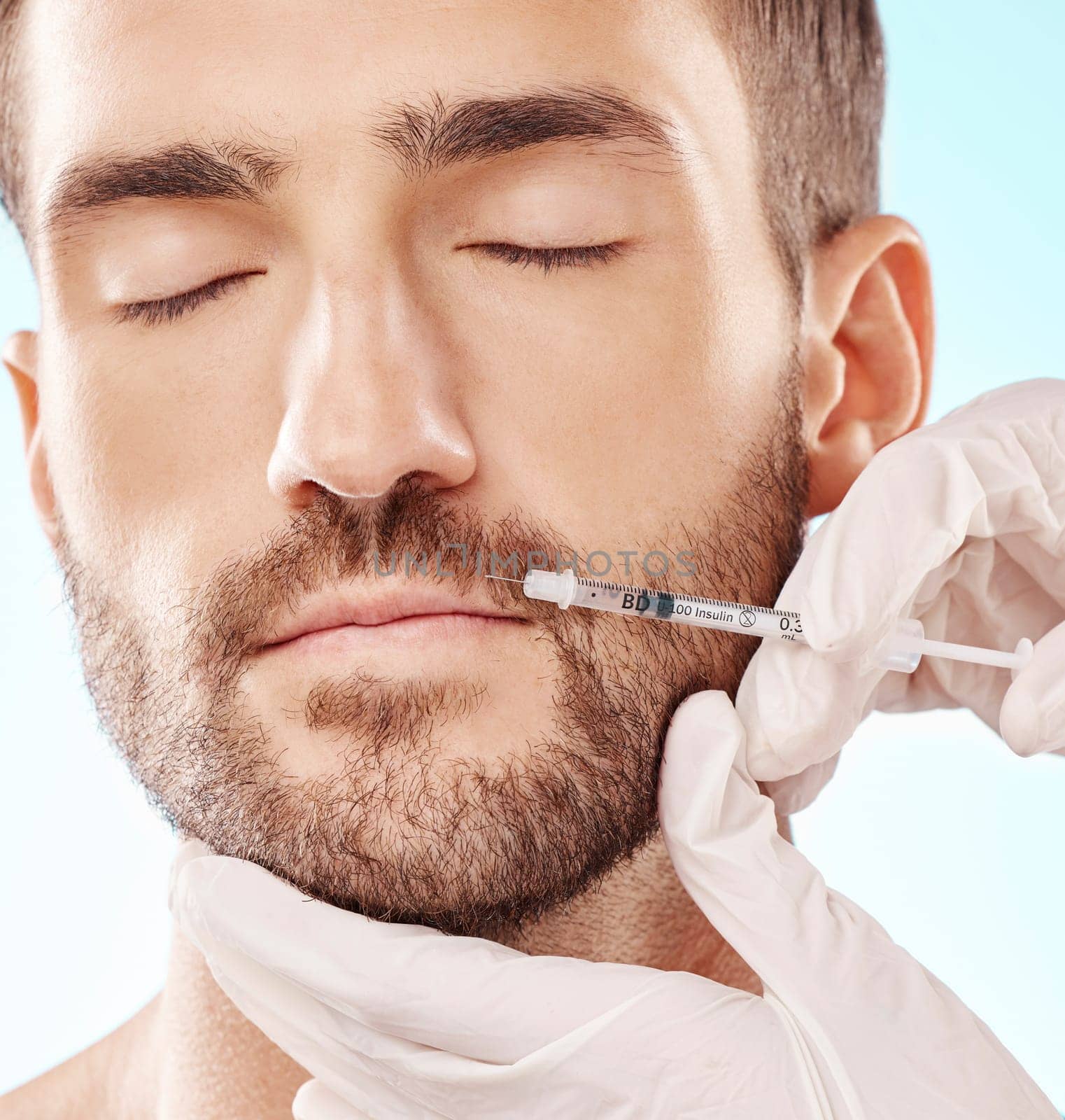 Man, lip filler and mesotherapy with face, hands and needle syringe, injection and beauty on blue background. Dermatology, cosmetic care and procedure, health and skincare with wellness and collagen by YuriArcurs