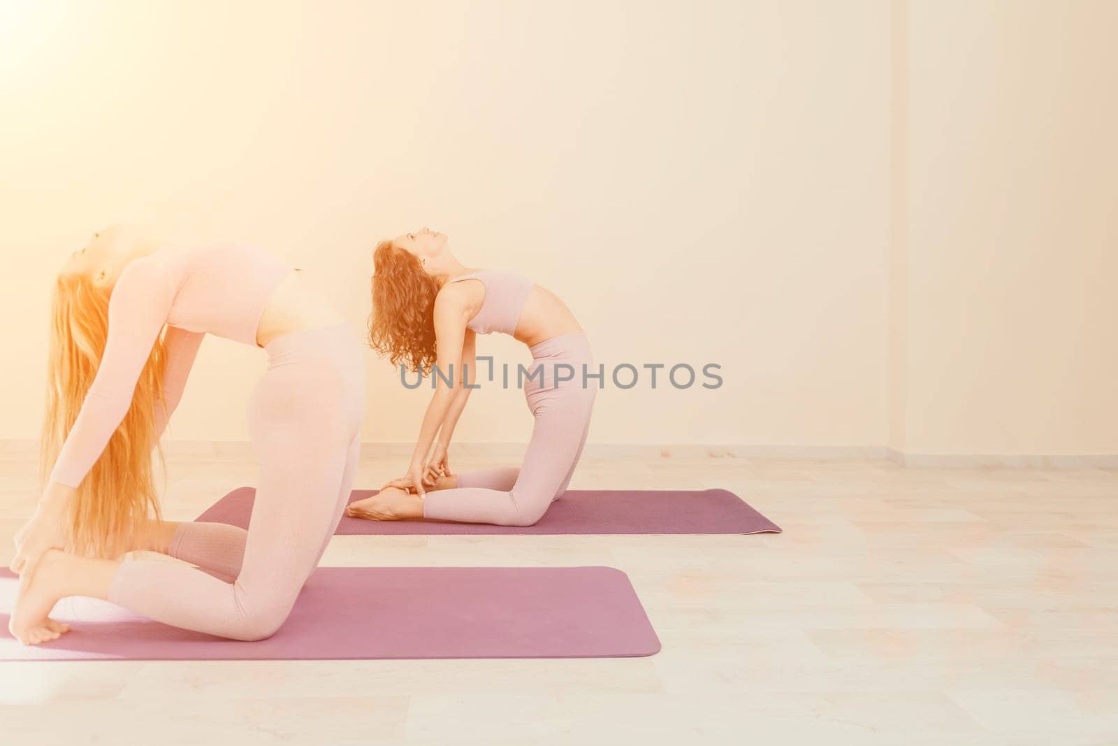 Young woman with long hair in white swimsuit and boho style braclets practicing outdoors on yoga mat by the sea on a sunset. Women's yoga fitness routine. Healthy lifestyle, harmony and meditation