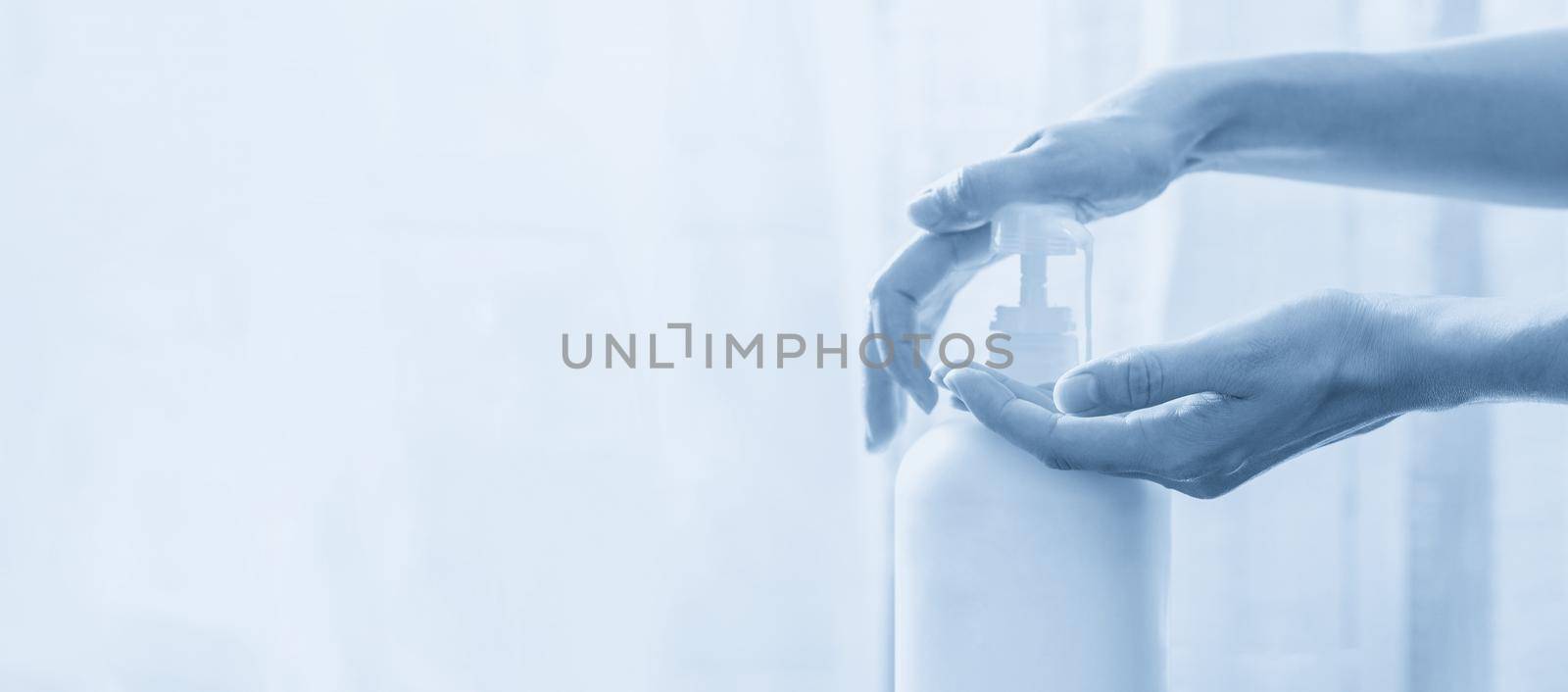 Woman hands pushing pump plastic soap bottle on white background with copy space by Mariakray