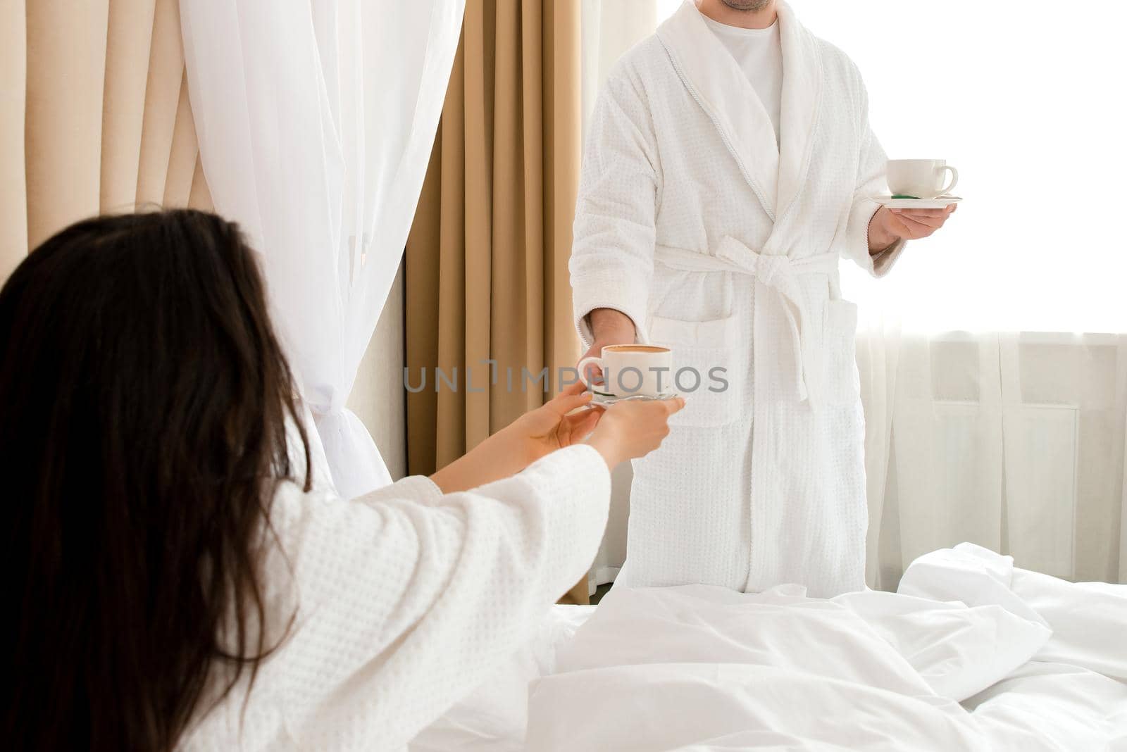 Man bringing coffee to his girlfriend in bed