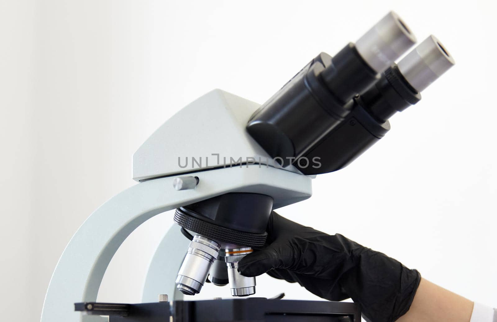 Closeup of microscope and hands wearing rubber gloves in modern laboratory . High quality photo