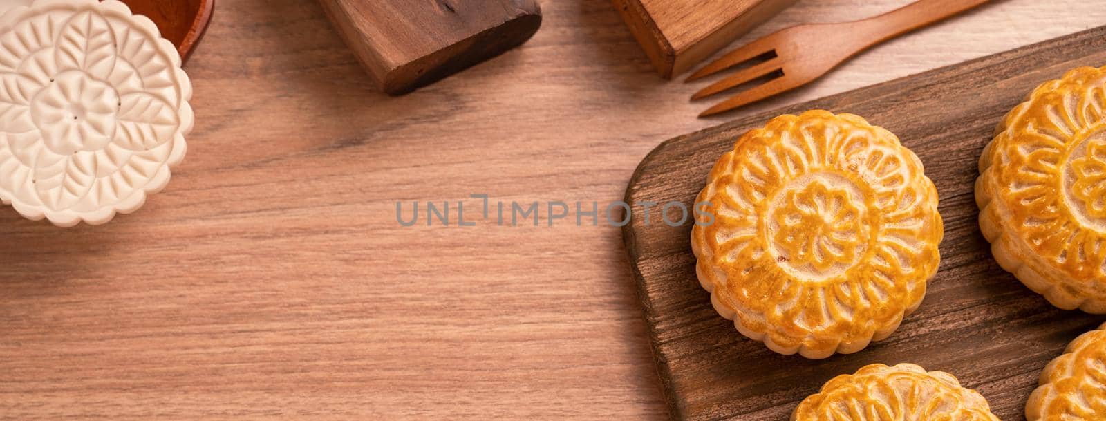 Round shaped moon cake Mooncake - Chinese style pastry during Mid-Autumn Festival / Moon Festival on wooden background and tray, top view, flat lay. by ROMIXIMAGE