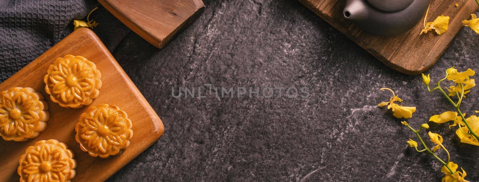 Mid-Autumn Festival traditional food concept - Beautiful Moon cake on black slate table with tea, pastry mold, flower, top view, flat lay, copy space by ROMIXIMAGE
