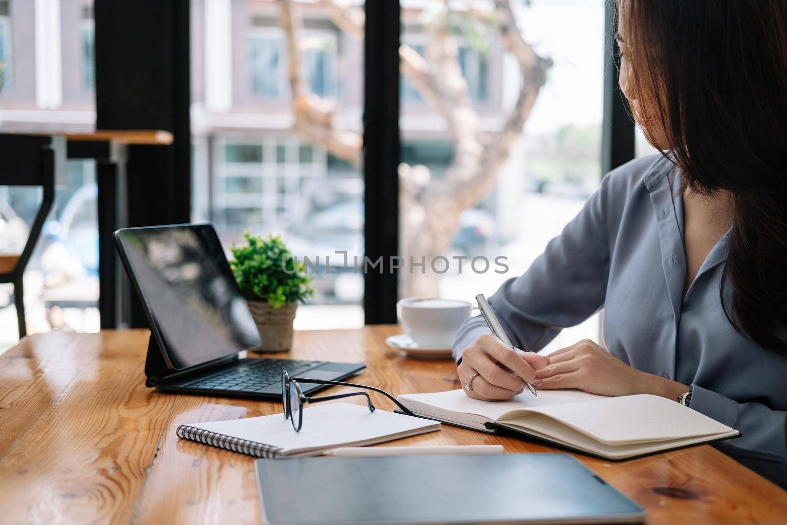 business asian woman hand taking notes with various items placed on the office table. online meeting, online learning concept.