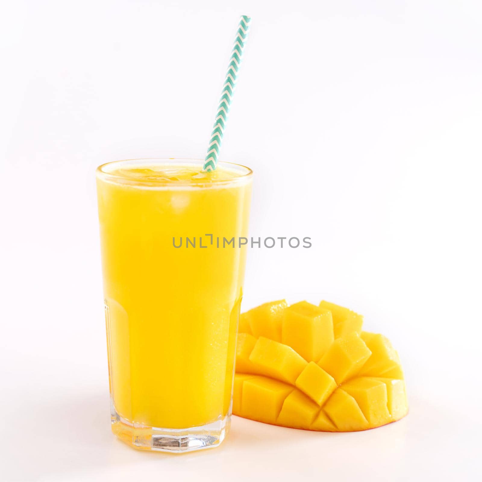 Fresh tropical mango juice with beautiful diced pulp and striped paper straw isolated on white background table, close up, cut out, clipping path.