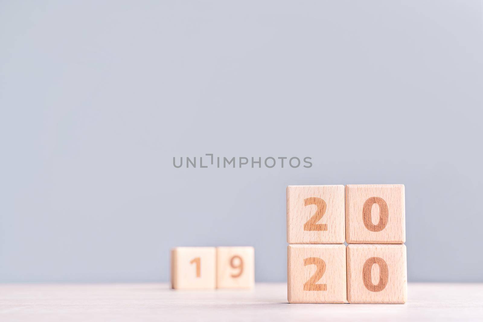 Abstract 2020 & 2019 New year countdown design concept - wood blocks cubes on wooden table and low saturation blue background, close up, copy space.