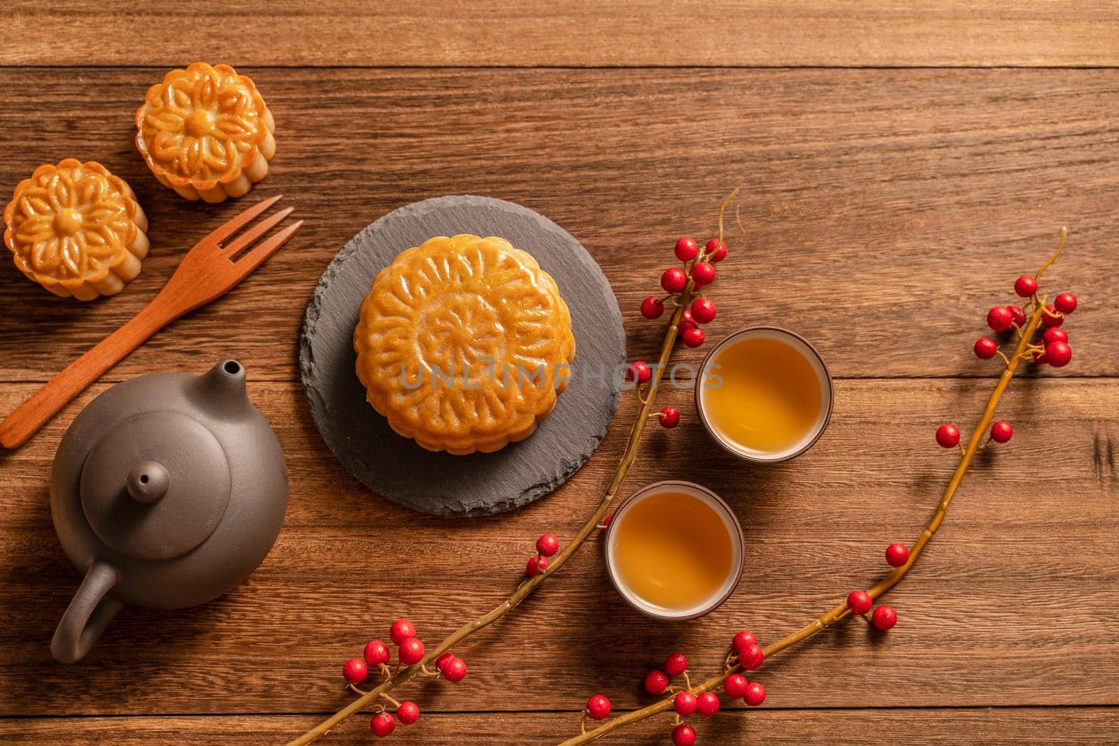 Chinese traditional pastry Moon cake Mooncake with tea cups on bamboo serving tray on wooden background for Mid-Autumn Festival, top view, flat lay.