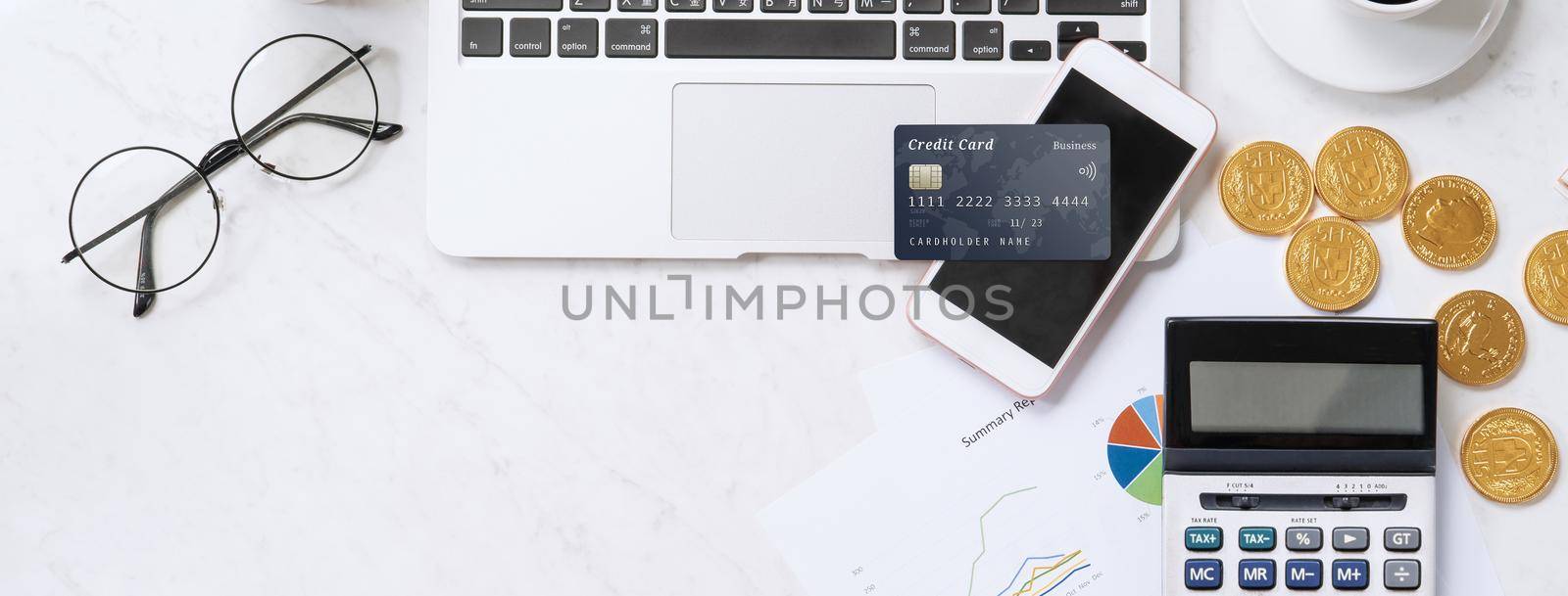 Concept of online payment with credit card with smart phone, laptop computer on office desk on clean bright marble table background, top view, flat lay