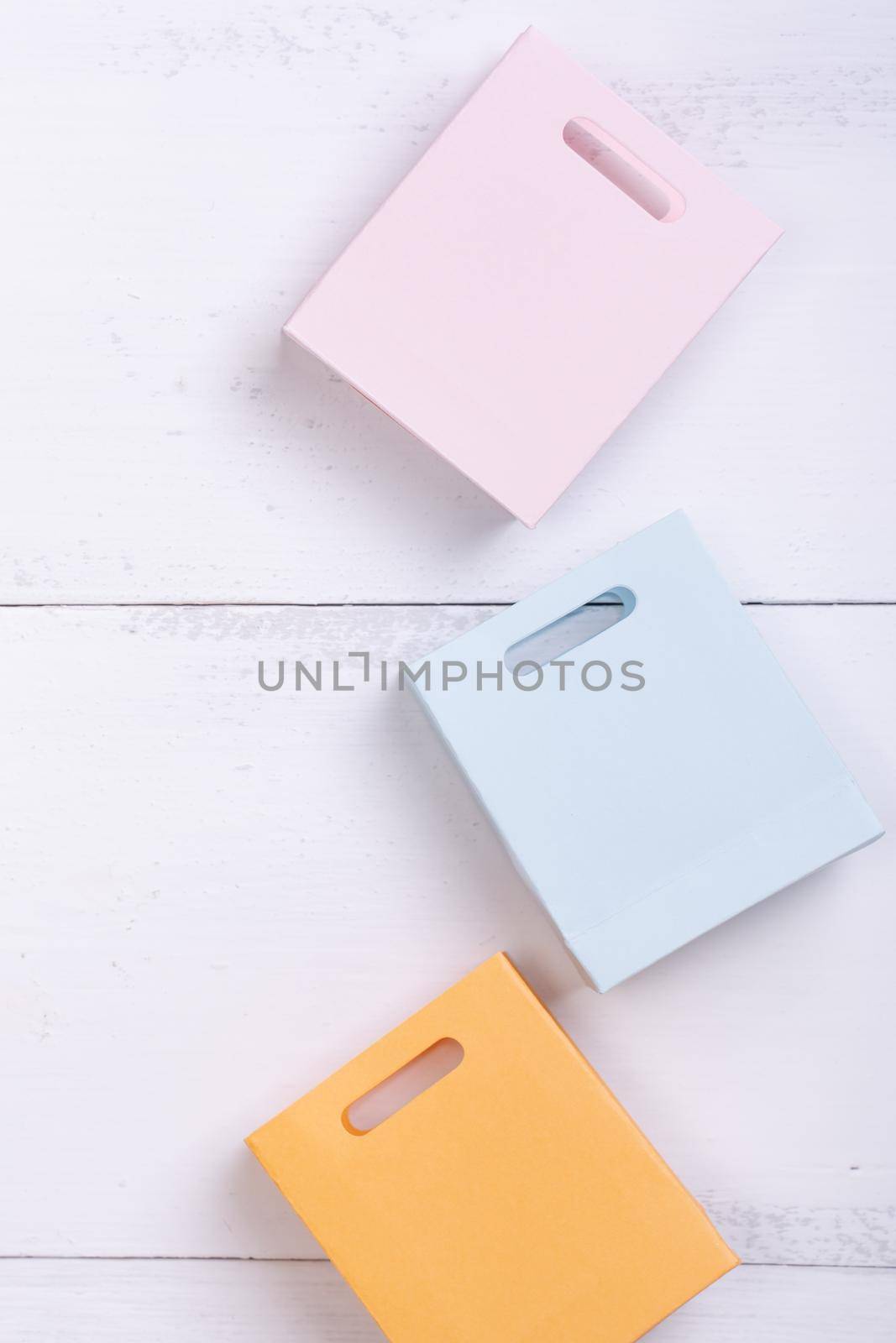 Abstract design element, annual sale, shopping season concept, mini cart with colorful paper bag on white wooden table background, top view, flat lay