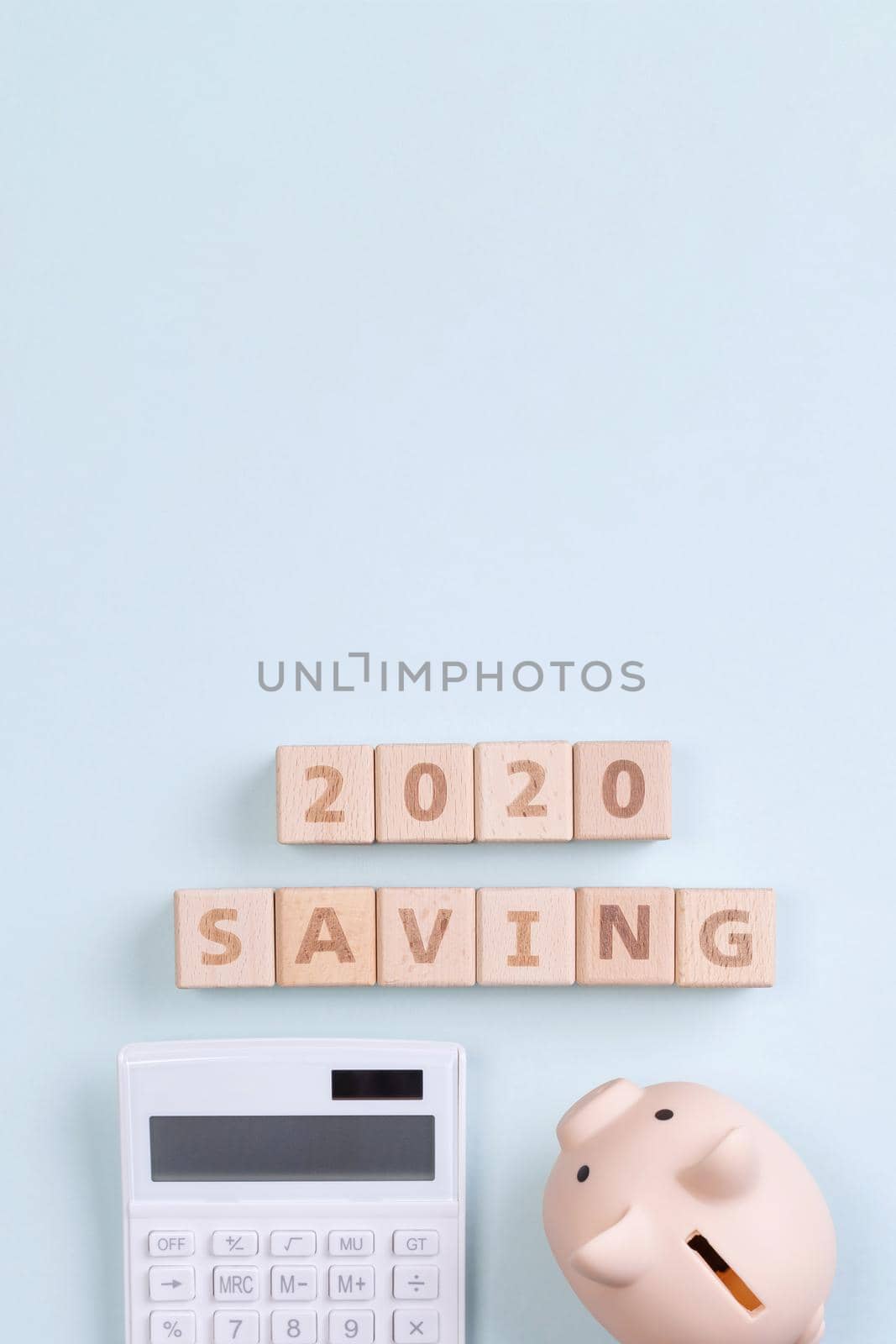 2020 goal, finance plan abstract design concept, wood blocks on blue table background with piggy bank and calculator, top view, flat lay, copy space.