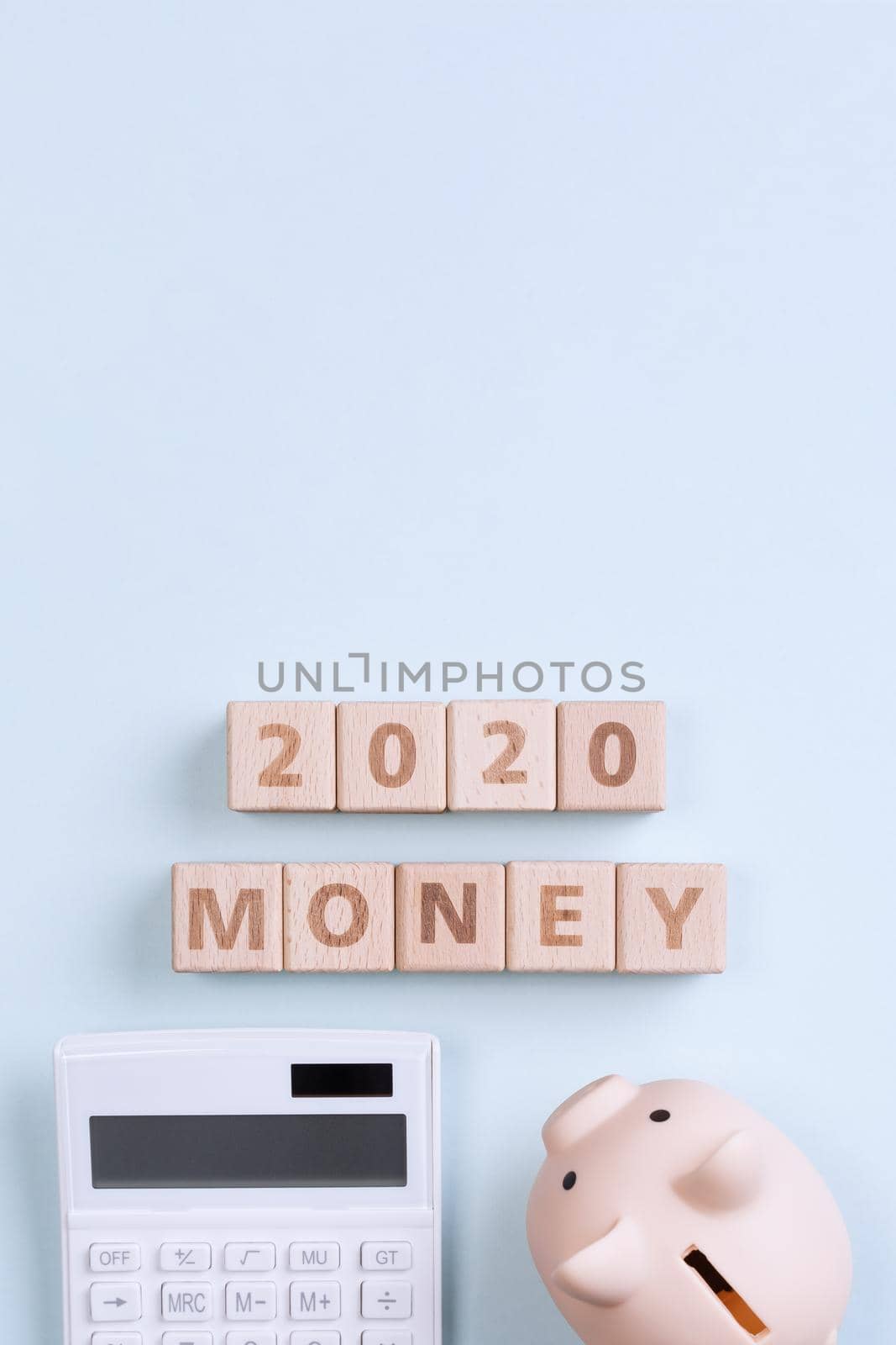 2020 goal, finance plan abstract design concept, wood blocks on blue table background with piggy bank and calculator, top view, flat lay, copy space.