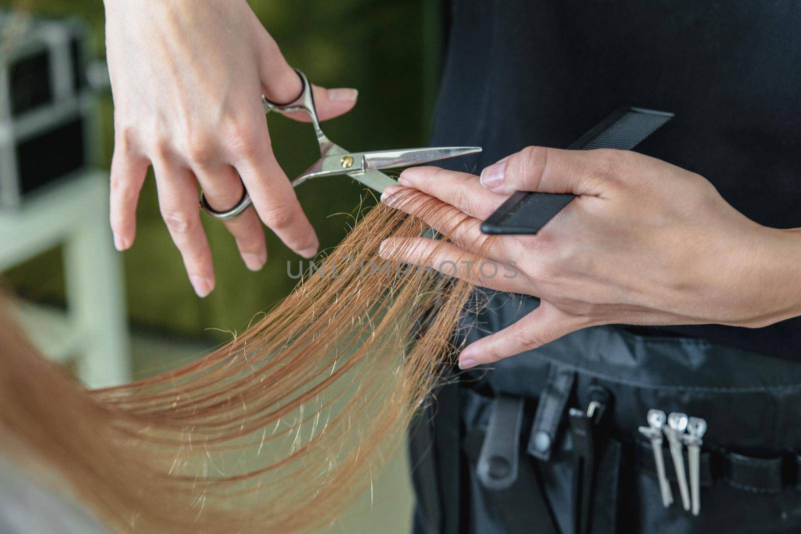 Hairdresser cut hair of a blonde girl