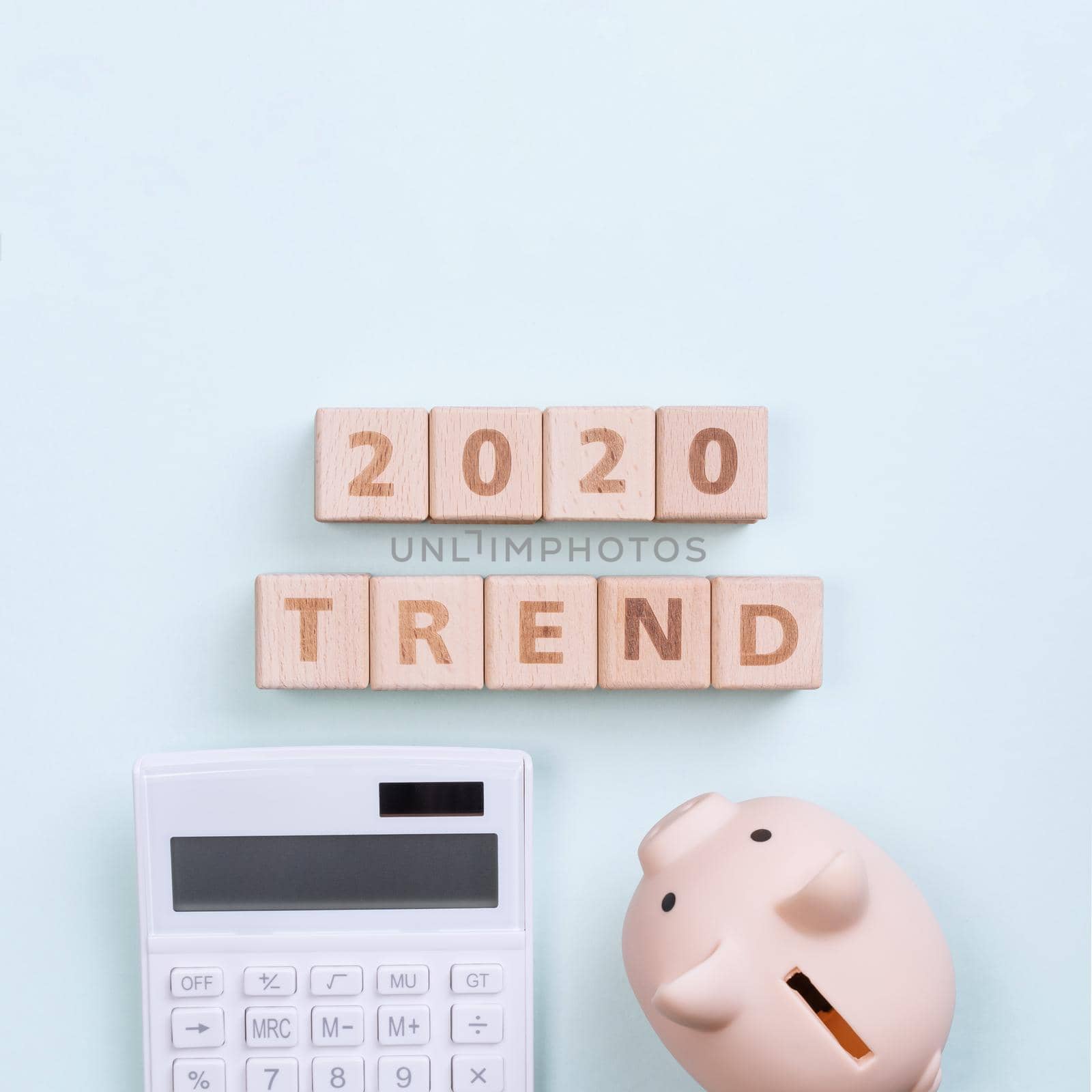 2020 goal, finance plan abstract design concept, wood blocks on green table background with piggy bank and calculator, top view, flat lay, copy space.