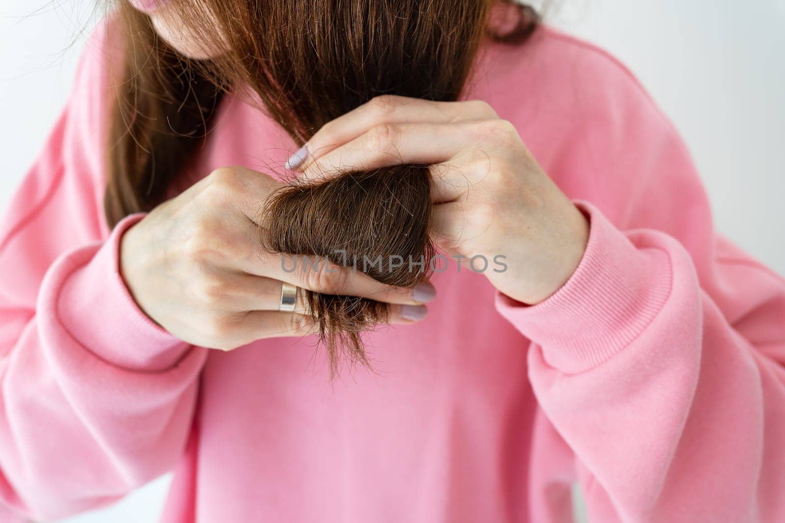 The concept of split ends, unhealthy hair. Close up portrait of frustrated unhappy sad woman showing damaged hair