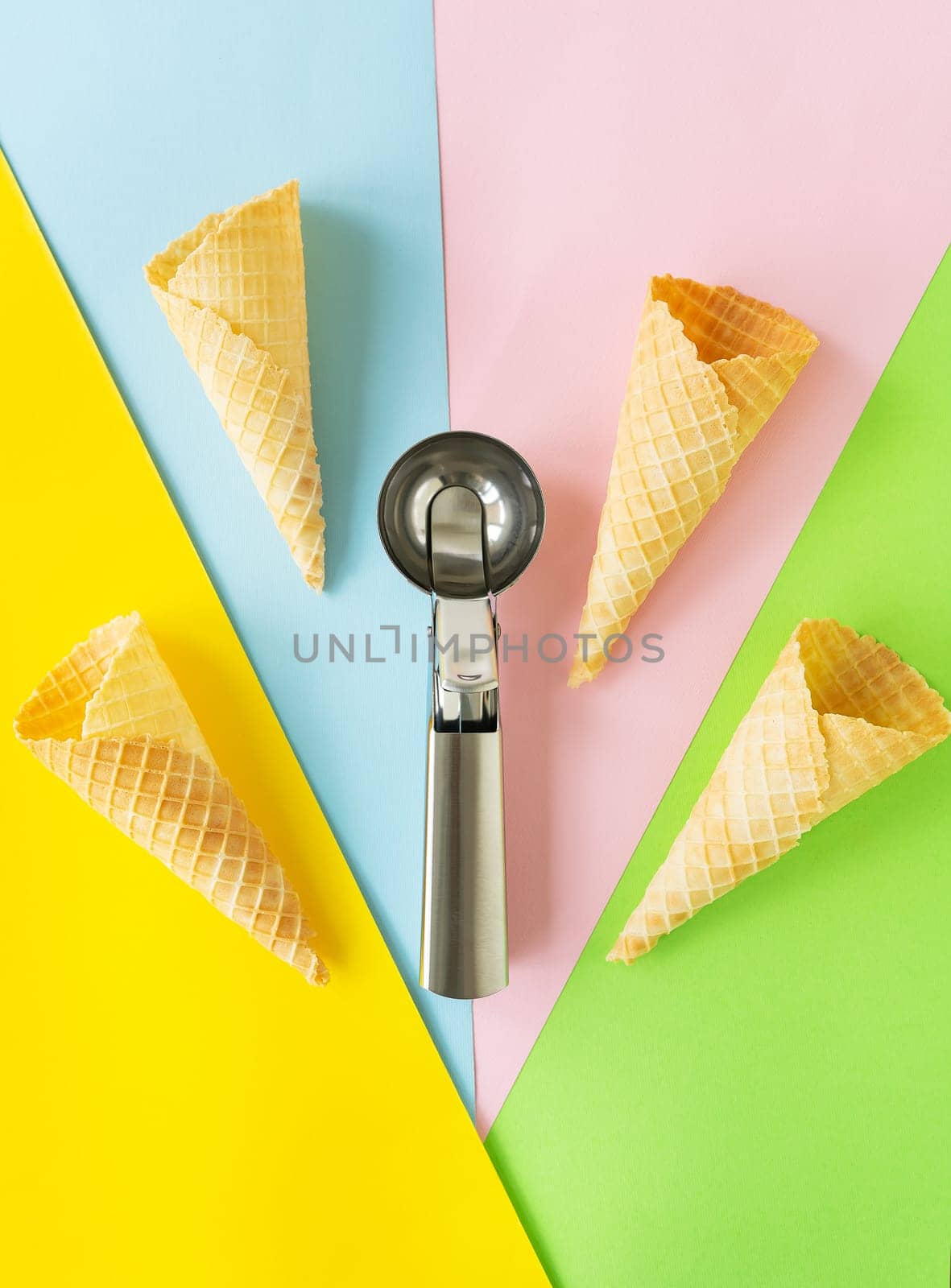 Wafer cups on a multi-colored bright background along with a metal spoon. Takeaway ice cream concept, vertical photo. by sfinks