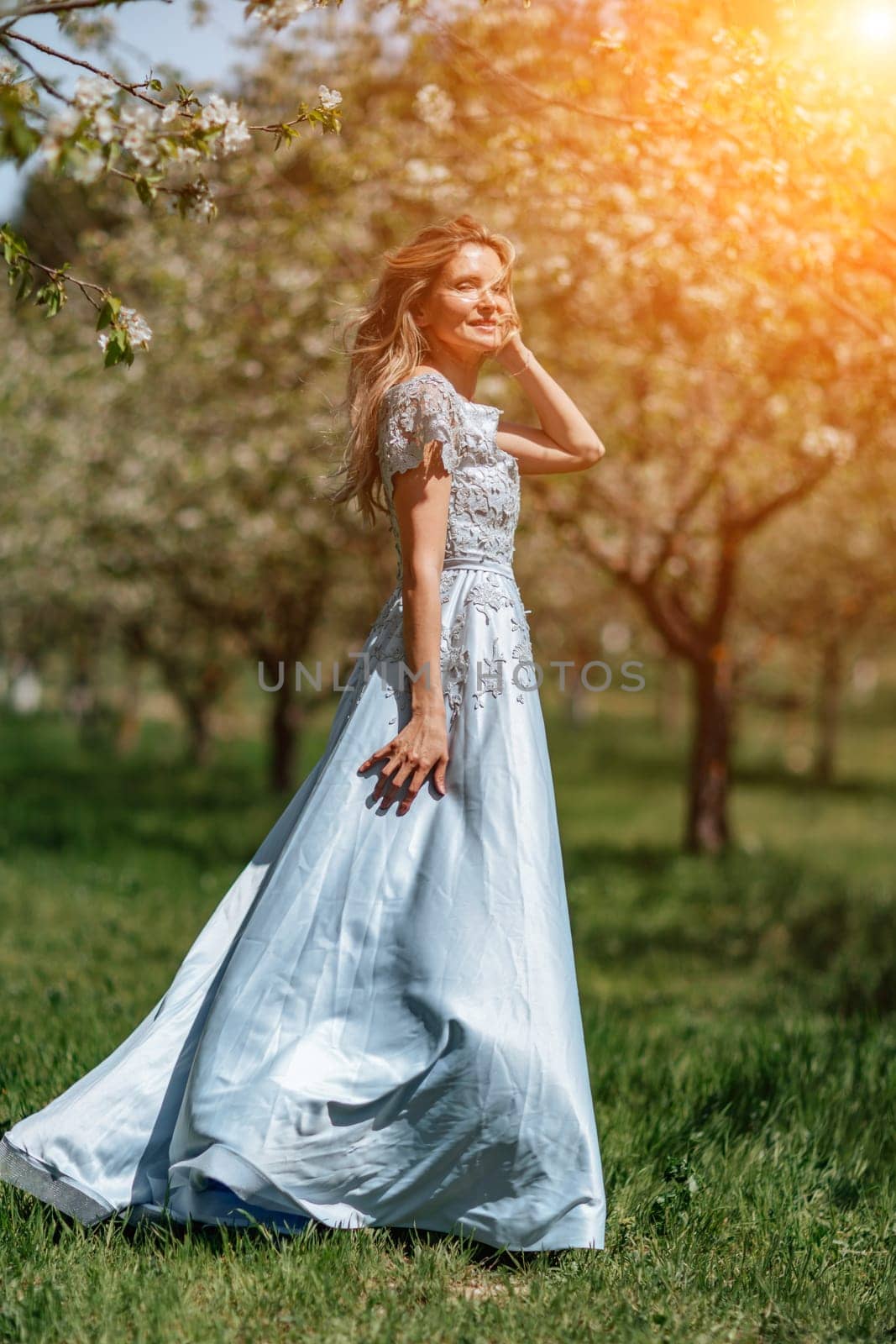 Portrait of a blonde in the park. Happy woman with long blond hair in a blue dress