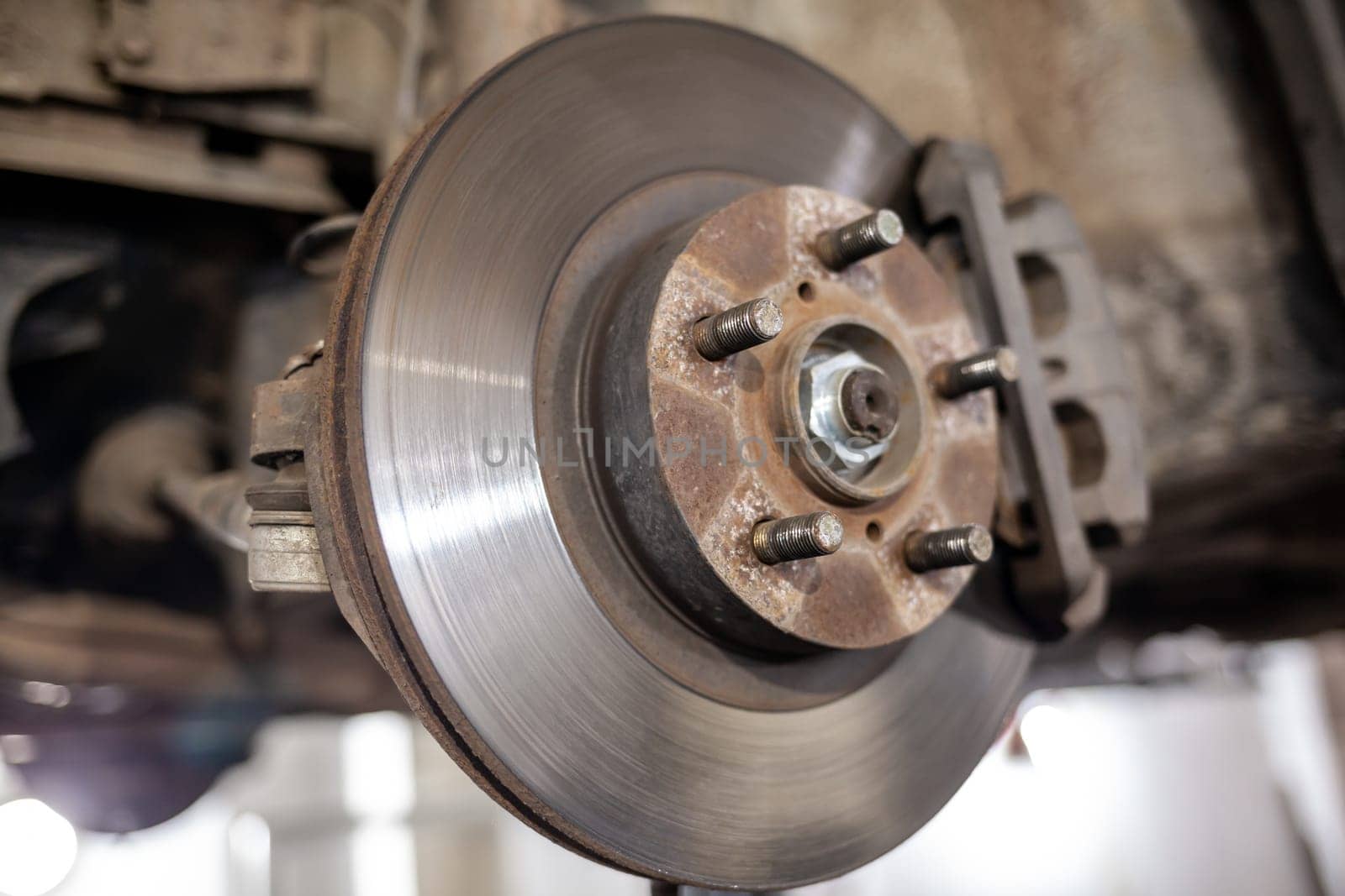 Disc brake of the vehicle for repair, in process of new tire replacement. Car brake repairing in garage.Suspension of car for maintenance brakes and shock absorber systems. Replacement of brake pads.