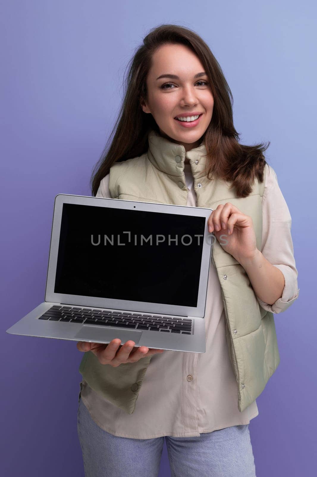 young brunette woman freelancer showing laptop screen with mockup for advertising.