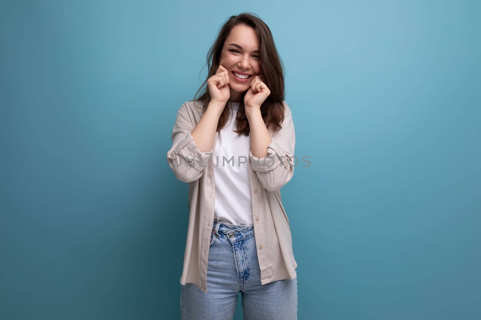 brunette young female adult in shirt and jeans smiling on background with copy space.