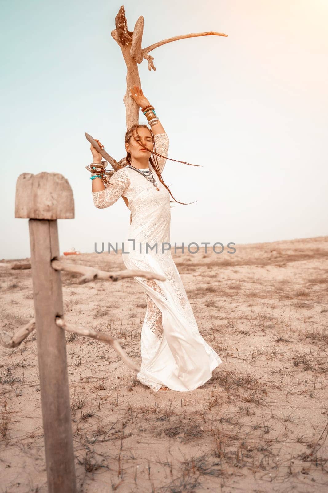 woman sea white dress. Model in boho style in a white long dress and silver jewelry on the beach. Her hair is braided, and there are many bracelets on her arms