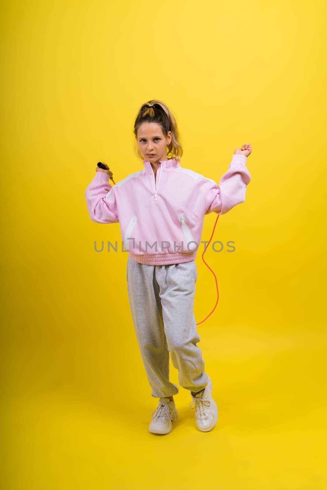 Adorable female child with skipping rope jumping in a studio