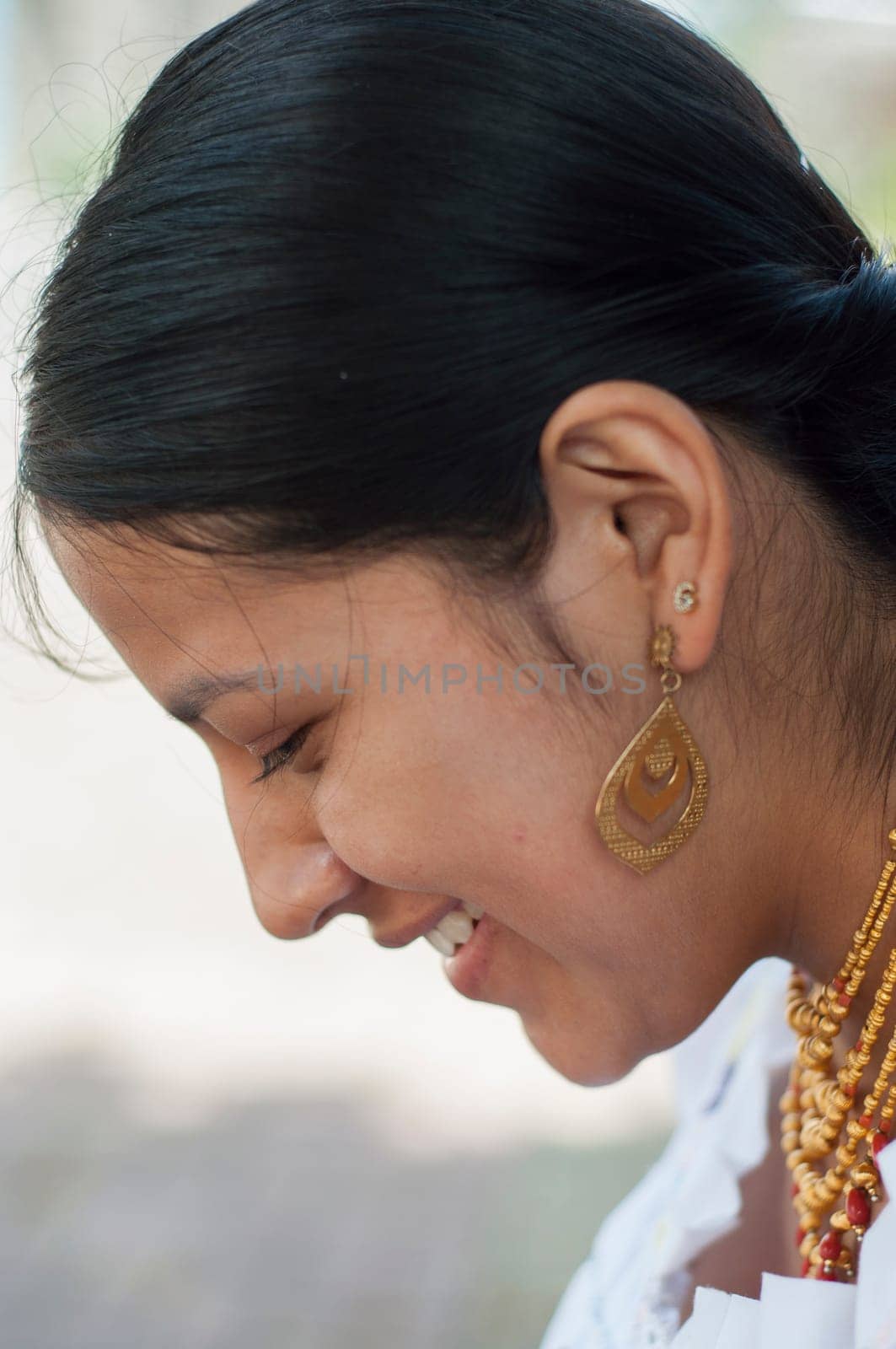 close-up of the profile of a pretty native woman with traditional earrings and necklaces and typical indigenous dress by Raulmartin