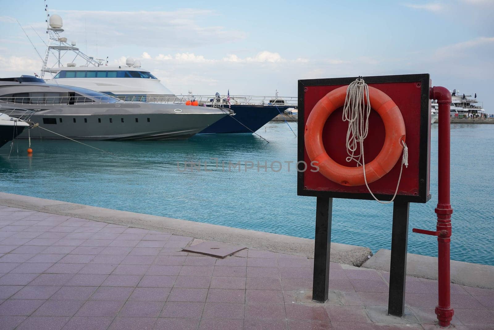 red lifebuoy at a blue ocean bay with a luxury yacht in the background. High quality photo